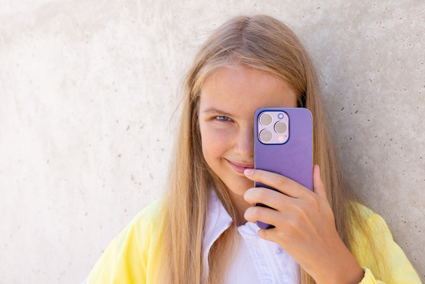 Adolescente tenant la caméra du téléphone mobile devant son œil - Photo, image