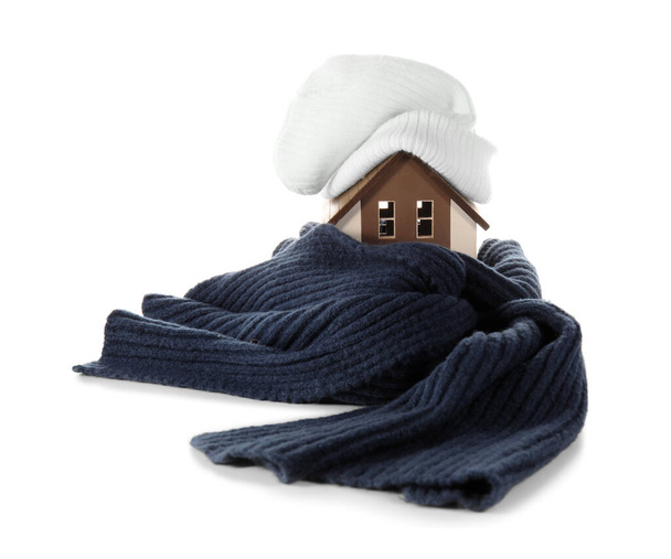 Hausmodell mit Hut und Schal auf weißem Hintergrund. Heizkonzept - Foto, Bild