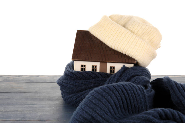 House model with hat and scarf on table against white background. Heating concept - Photo, Image