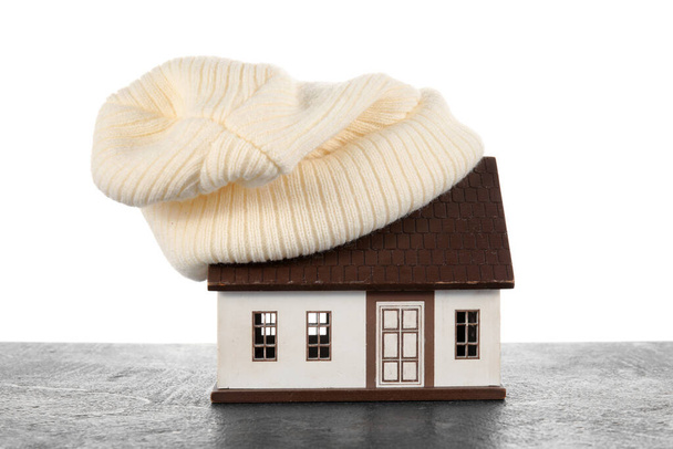白い背景に暗いテーブルの上に帽子と家のモデル。暖房コンセプト - 写真・画像