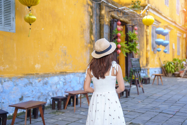 Счастливый взгляд на древний город Хой в центральном Вьетнаме, женщина в платье и шляпе путешествует. ориентир и популярны для туристических достопримечательностей. Концепция путешествий по Вьетнаму и Юго-Восточной Азии - Фото, изображение