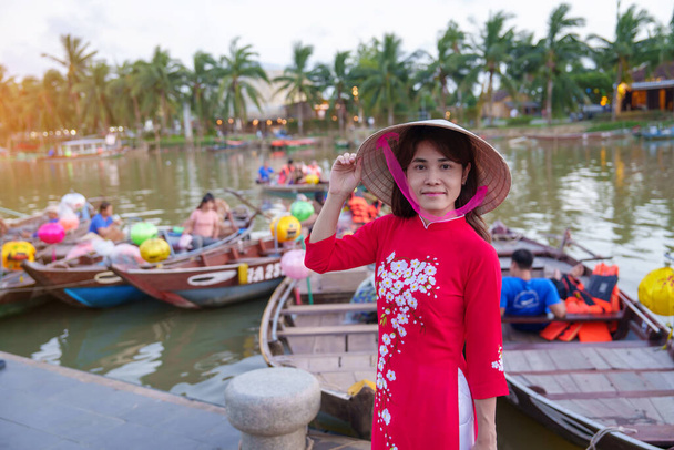 幸せな女性青大ベトナムのドレスを着て、旅行者は、古代の町ホイアンで木ボン川や観光船に乗るをご覧ください。観光地のランドマークベトナムと東南アジア旅行のコンセプト - 写真・画像