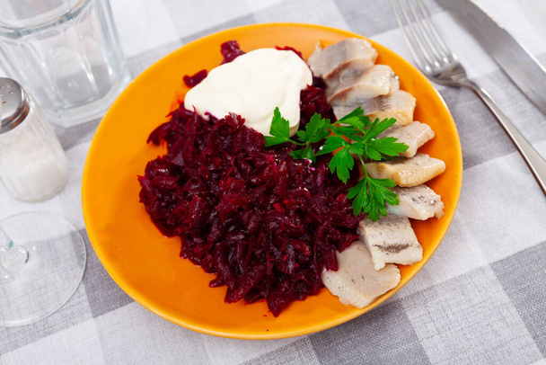 Appetizer of home-style pickled herring slices with grated beets and delicate mayonnaise garnished with fresh parsley. Russian cuisine.. - Photo, image