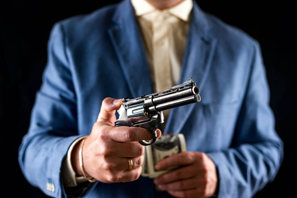 Sniper man in black suit gesturing and boldly holding gun on isolated black background. Concept for a killer. murders a criminal - Fotografie, Obrázek