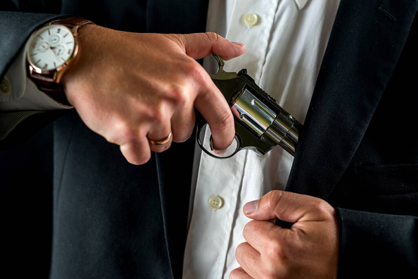 robber in tuxedo with gun at chest level isolated on plain background. male thief gun in hand - Φωτογραφία, εικόνα