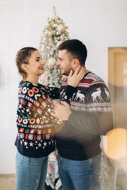 Szczęśliwa para w tradycyjnym swetrze dekorowanie choinki razem w domu - Zdjęcie, obraz