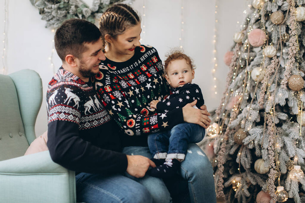 Ritratto di famiglia felice di madre padre e piccolo figlio riccio che festeggia il Natale insieme a casa. Il concetto di Vigilia di anno nuovo. - Foto, immagini