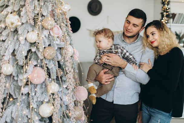 Portrait de famille heureuse de père mère et petit fils bouclé célébrant Noël ensemble à la maison. Le concept du réveillon du Nouvel An. - Photo, image