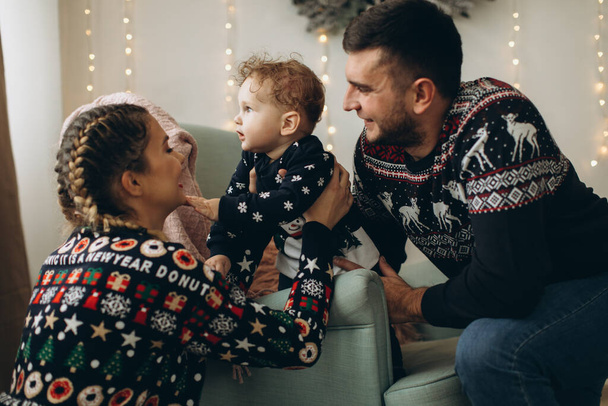 Портрет счастливой семьи отца матери и маленького кудрявого сына, празднующего Рождество вместе дома. Новогодняя концепция. - Фото, изображение