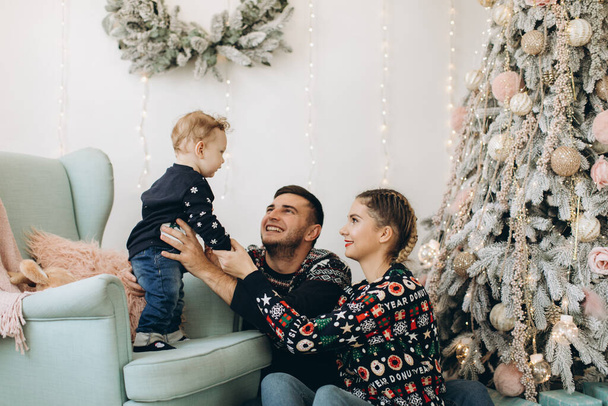Retrato de familia feliz de padre madre y pequeño hijo rizado celebrando la Navidad juntos en casa. Concepto de Nochevieja. - Foto, imagen