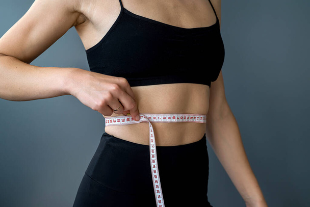 detailní záběr měřením trénovaného žaludku měřicí páskou. sport a fitness a dietní koncept. Měření rozměrů těla - Fotografie, Obrázek