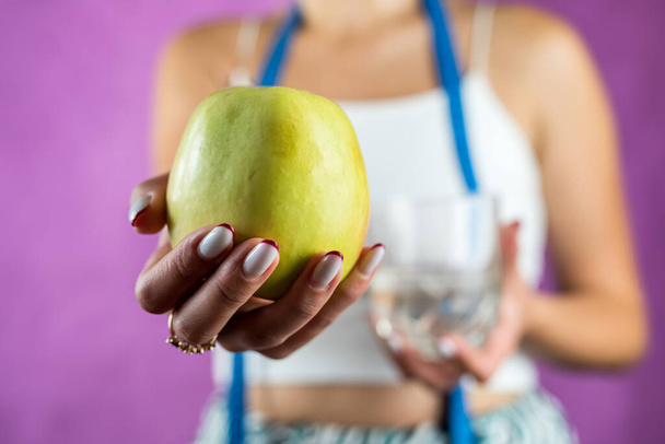 mujer se para antes de elegir una manzana o agua para bajar de peso .aislado sobre un fondo blanco. Concepto de dieta. Sanidad - Foto, imagen