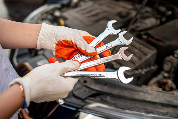 mécanicien de voiture répare un moteur de voiture près d'une voiture avec un capot ouvert. entretien de voiture. services de réparation. - Photo, image