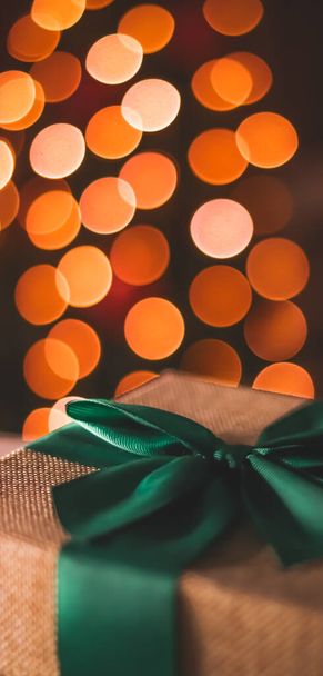 Wakacyjny nastrój i świąteczna atmosfera, zapakowany prezent i choinka światła na tle, zbliżenie - Zdjęcie, obraz