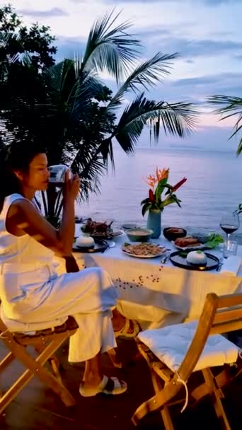 Aasian Thai naiset auringonlaskun aikana illallinen rannalla Koh Chang Thaimaa. - Materiaali, video