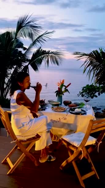 Azjatyckie Tajskie kobiety podczas zachodu słońca jedzące kolację na plaży Koh Chang Tajlandia podczas wakacji - Materiał filmowy, wideo