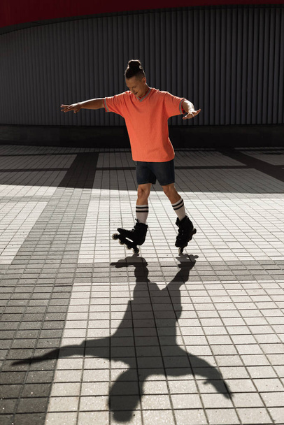 Smiling roller skater in casual clothes doing trick on urban street  - Fotoğraf, Görsel