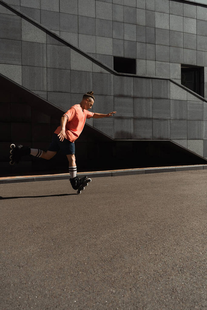 Side view of young roller skater riding on one leg on city street  - Φωτογραφία, εικόνα