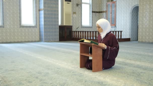 Koraani lausuminen Rahle, aasialainen muslimityttö istuu polvillaan lausuen koraania, islamilainen palvonta moskeijassa, muslimit elävät islam - Materiaali, video