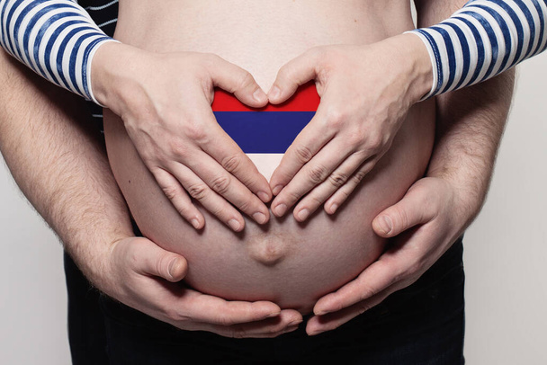 Сербська концепція. Чоловік, який обіймає вагітну жінку живіт і серце з прапором Сербії забарвлення - Фото, зображення