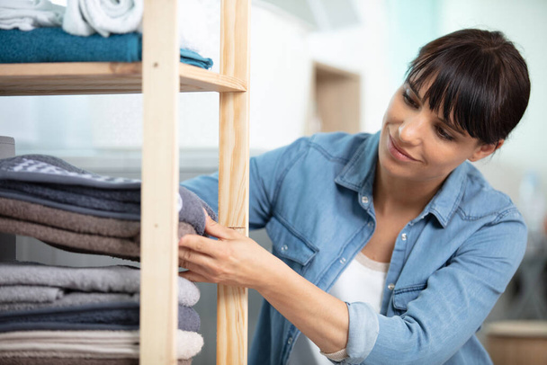 woman tidying clean laundry at home - Photo, image