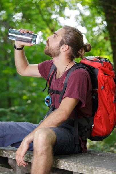 a young man drinking water outdoors - Fotó, kép