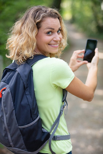 full length of a female hiker walking with cell-phone - Φωτογραφία, εικόνα
