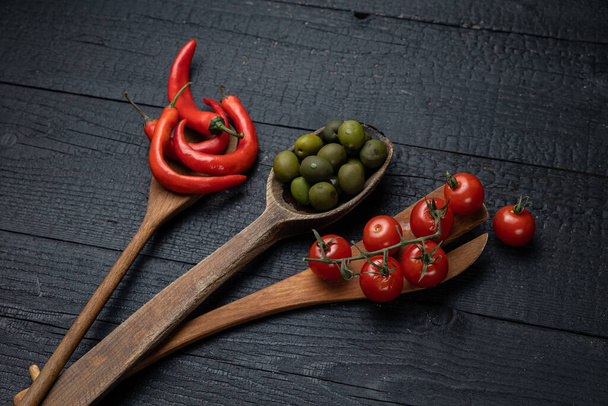 Wooden spoon on a dark background with vegetables - Foto, immagini