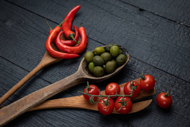 Wooden spoon on a dark background with vegetables - Foto, Imagen