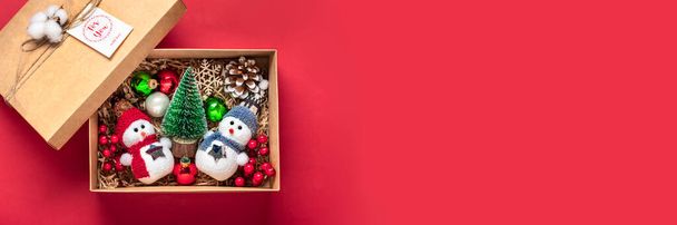 Handgemachtes Pflegepaket, saisonale Geschenkschachtel mit Spielzeug, Weihnachtsdekor auf rotem Tisch Personalisierter umweltfreundlicher Korb für Familie, Freunde, Mädchen für 24 Dezember, Weihnachten, Neujahr. - Foto, Bild