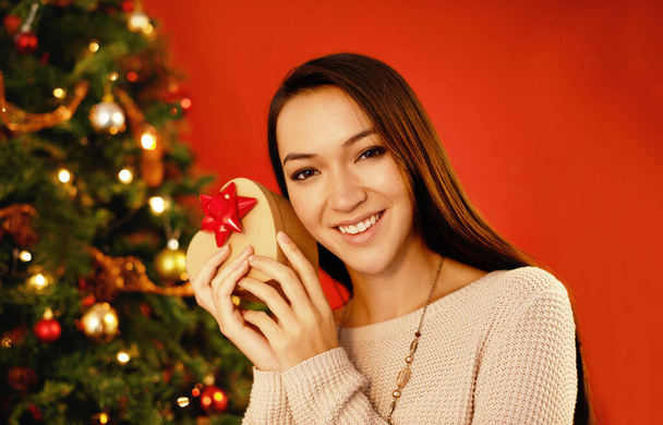 Let me guess...an attractive young woman holding up her christmas present to guess what it is - Photo, image