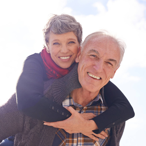 Se aferran a su entusiasmo por la vida. Retrato de una feliz pareja de ancianos disfrutando de un paseo a cuestas al aire libre - Foto, imagen