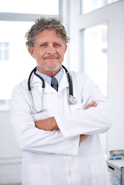 彼は健康の英雄だ。彼のオフィスに立つ笑顔の成熟した医師の肖像画 - 写真・画像