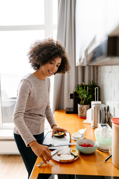 African american young woman with curly afro hairstyle making breakfast in morning at home - Fotoğraf, Görsel