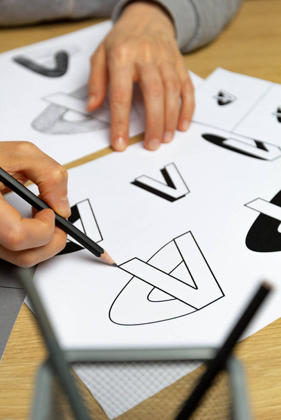 Projektant graficzny opracowuje logo marki. Ilustrator rysuje szkice na papierze. - Zdjęcie, obraz