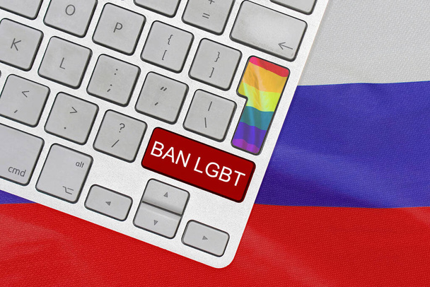 Белая компьютерная клавиатура с кнопкой флага ЛГБТ и красной кнопкой с текстом запрета ЛГБТ на фоне флага России. Запрет ЛГБТ-пропаганды в России. Запрет на ЛГБТ в России - Фото, изображение