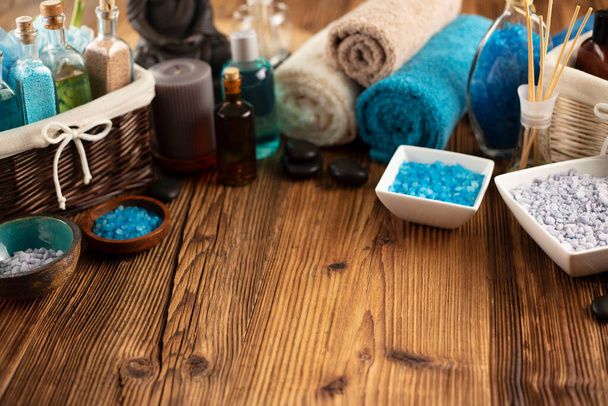 Spa and wellness concept. Bottles with bath and spa cosmetics, rolled up towels, bath salts and care products on wooden rustic paneling. - Fotoğraf, Görsel