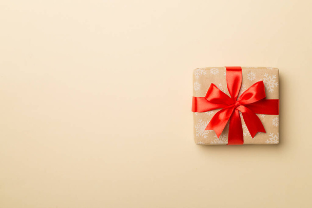 Caja de regalo con lazo de cinta roja sobre fondo de color, vista superior. - Foto, imagen