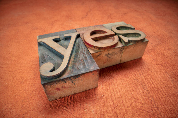 yes - word in wooden letterpress printing blocks, stained by dark color inks, macro shot against textured bark paper, confirmation concept - Valokuva, kuva