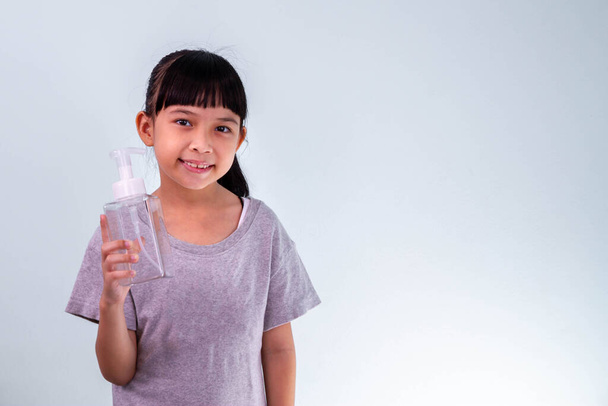 Mała Azjatka dziecko umieścić alkohol żel do dezynfekcji pompy na ręce do czyszczenia lub mycia rąk. - Zdjęcie, obraz