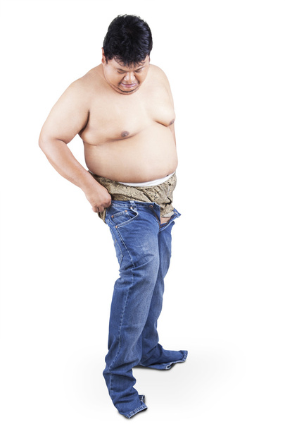 Man with fat body try to wear his old jeans - 写真・画像