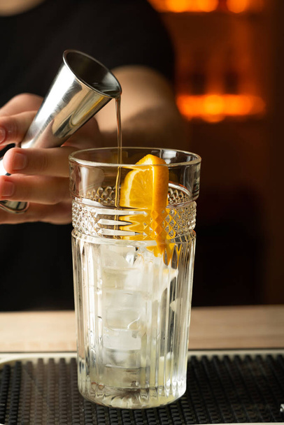 Bartender pouring a gin from the steel jigger to the glass on the bar counter. Copy space - Foto, Imagen