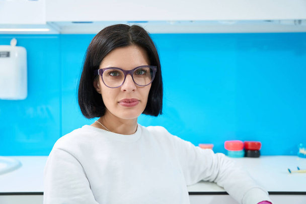 Femme médecin sur le lieu de travail dans un établissement médical, elle est en uniforme blanc et lunettes - Photo, image