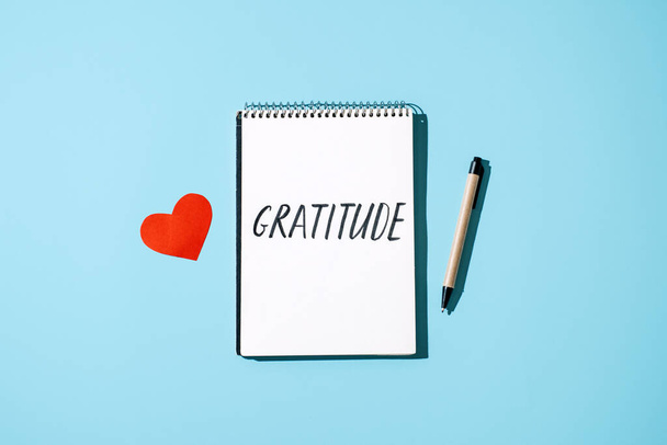 Hogyan gyakoroljuk a hálát. Szavak hálája nyitott füzetben az asztalon. Vedd észre, hogy értékeled a jó dolgokat, fejezd ki a háládat magadnak. Word hála és piros szív nyitott notebook kék háttér. - Fotó, kép