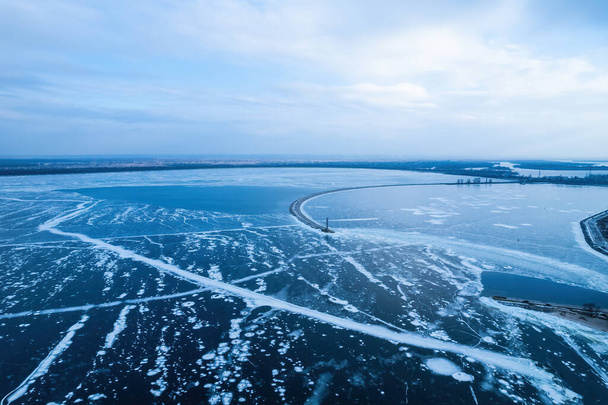 凍結した海の孤独な灯台の空中ビュー。亀裂の凍結青氷、ドローンビュー - 写真・画像