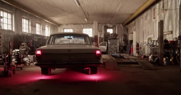 Handschuss von Retro-Limousine mit leuchtenden Rückleuchten, die während des Arbeitstages in sonnendurchfluteter Garage geparkt war - Filmmaterial, Video