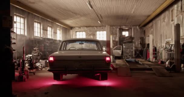 Handschuss von Retro-Limousine mit leuchtenden Rückleuchten, die während des Arbeitstages in sonnendurchfluteter Garage geparkt war - Filmmaterial, Video