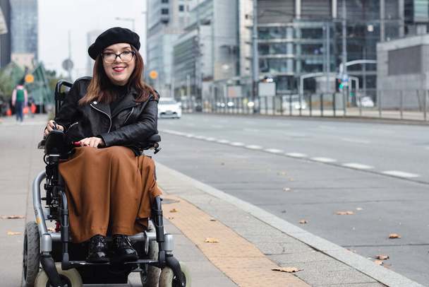 Брюнетка сидит в инвалидной коляске на городской улице. Высокое качество фото - Фото, изображение