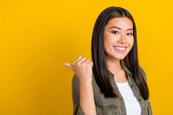 Photo of toothy beaming cheerful woman straight hairdo dressed gray shirt indicating empty space isolated on yellow color background. - Foto, Imagen