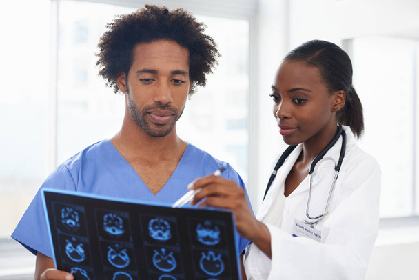 Es genial explicando los escáneres. una doctora afroamericana y un enfermero estudiando una tomografía computarizada - Foto, imagen